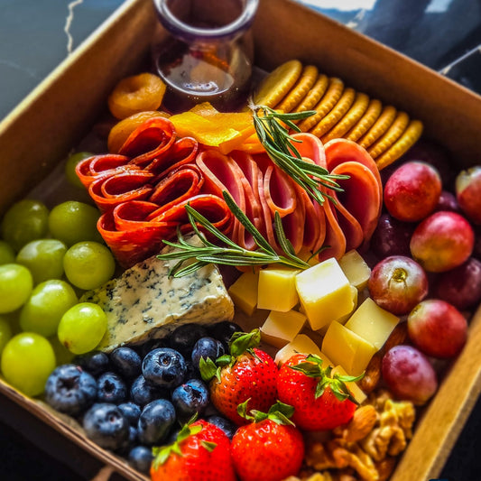 Assorted charcuterie board with meats, cheeses, fruits, and crackers in a boxbox.
